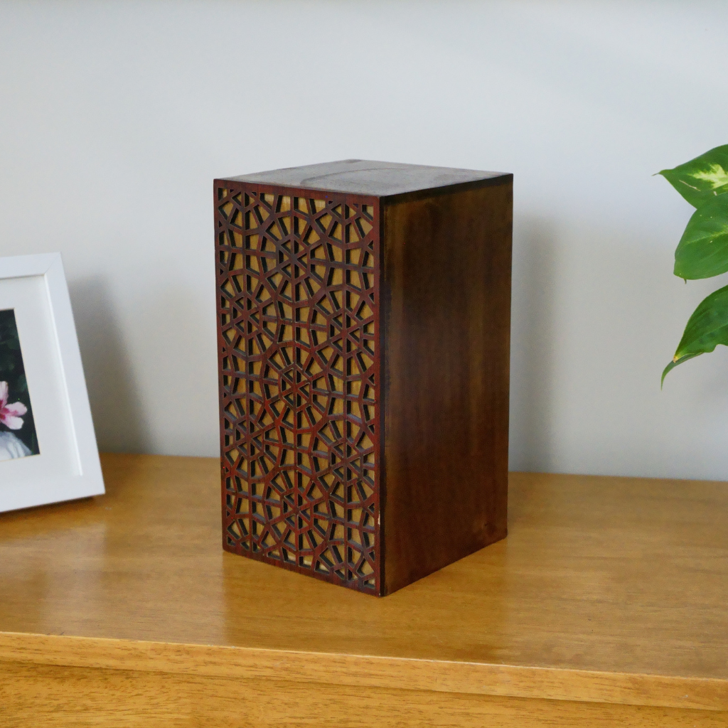 Wooden box urn with intricate circular details in natural setting