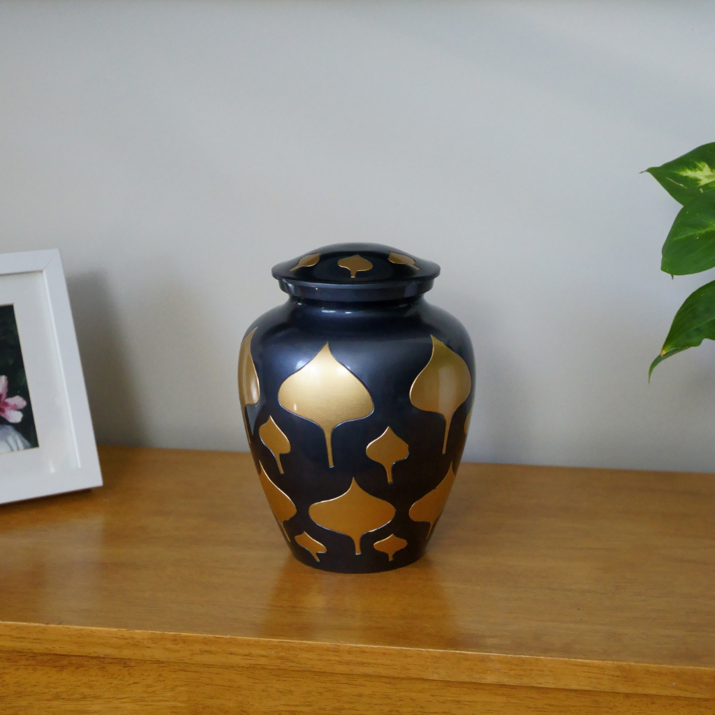 Black urn with gold leaf details in natural setting