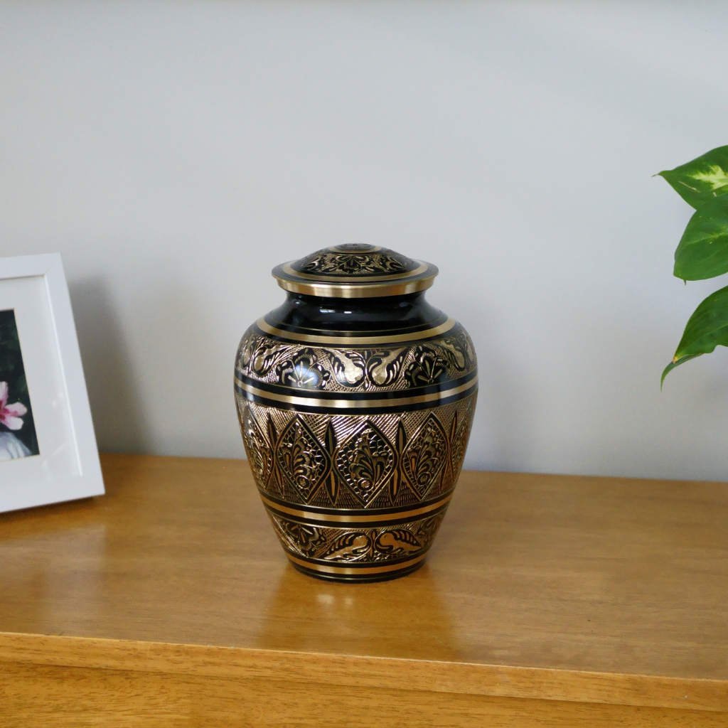 Brass urn with intricate butterfly details in natural setting