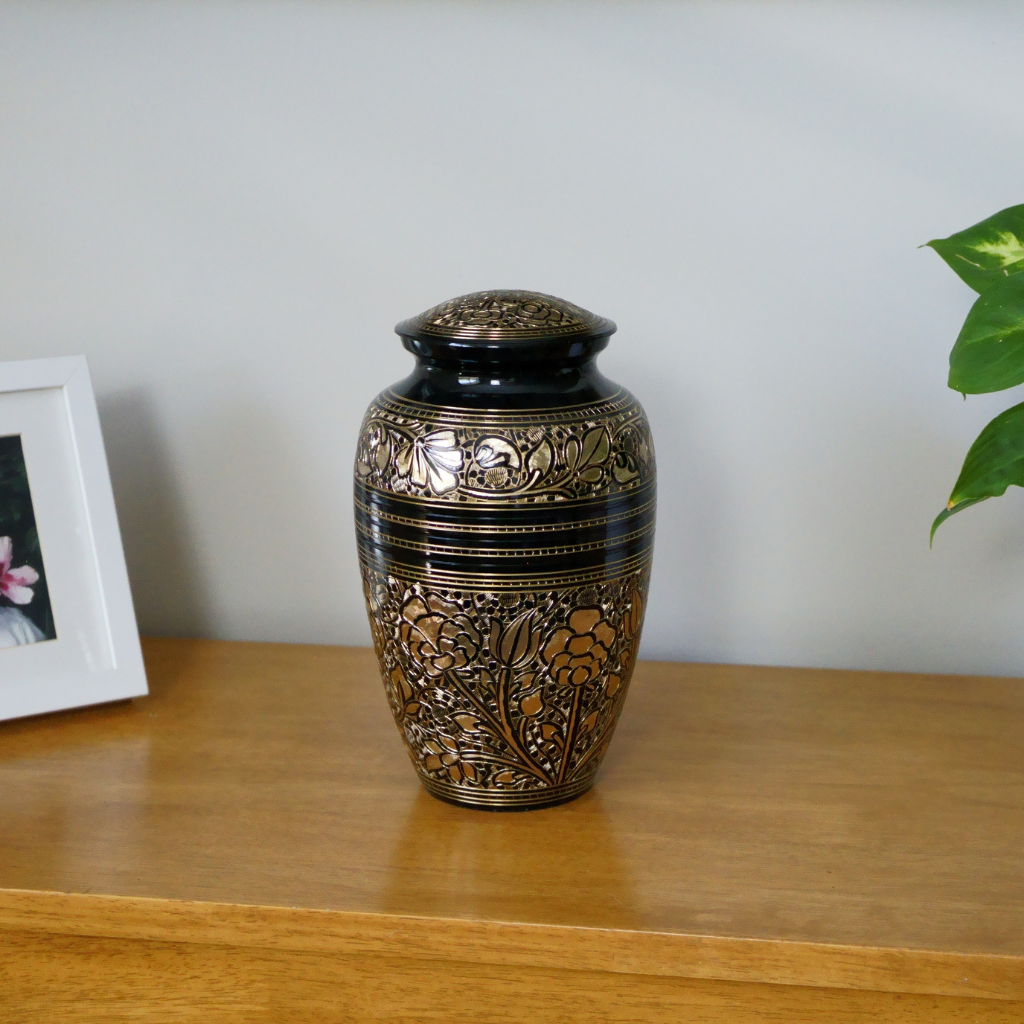 Black and gold brass urn with flower patterns in natural setting