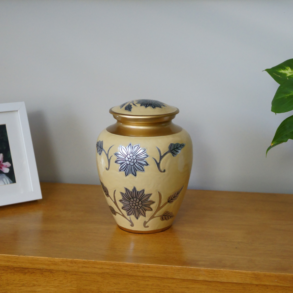 Yellow and gold urn with silver detailed floral patterns in natural setting