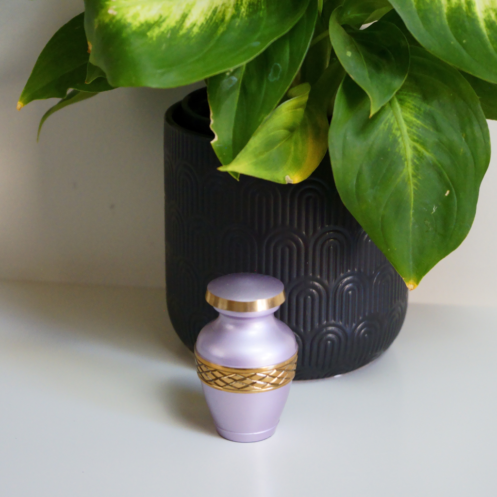 Pink keepsake urn with gold leaf details in natural setting