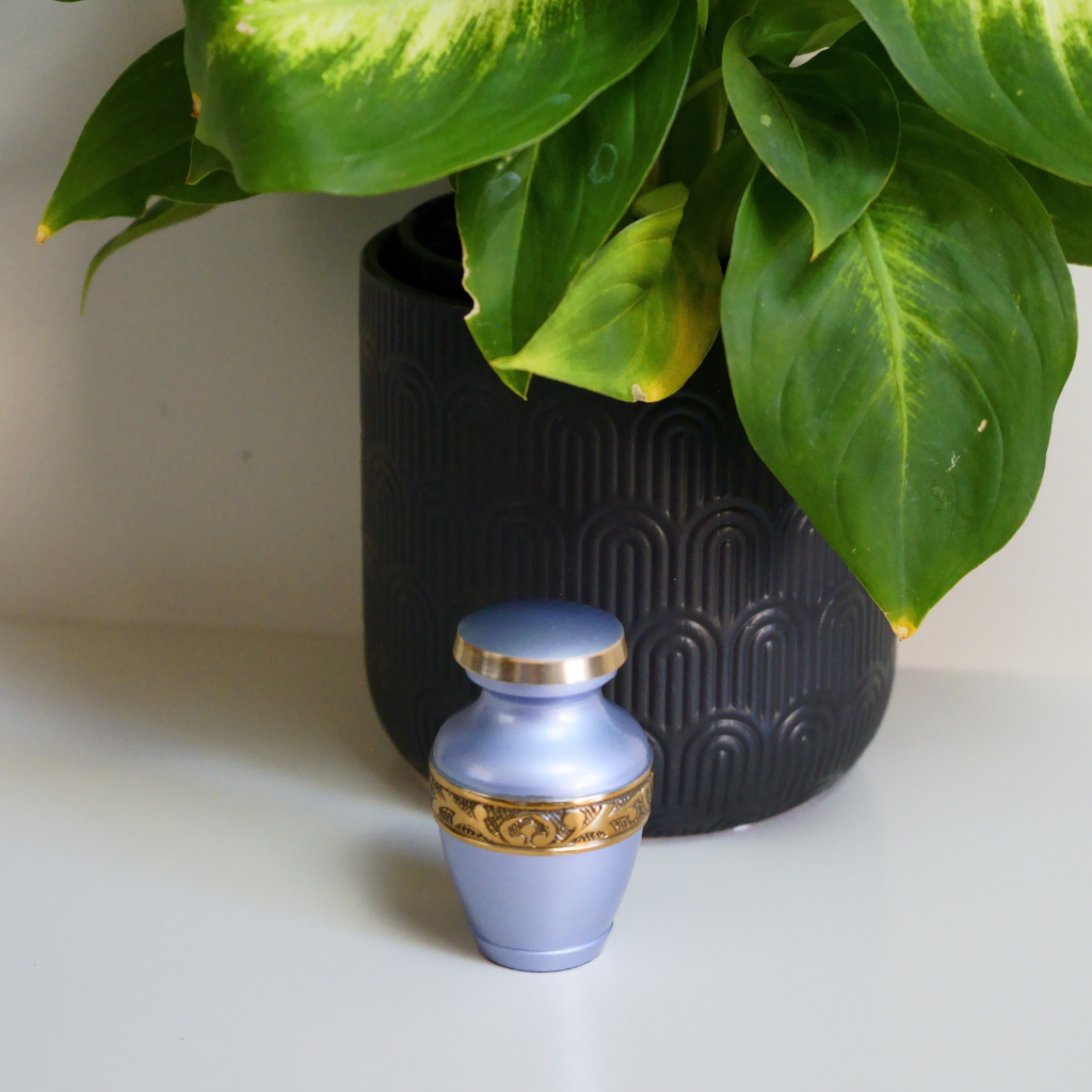Silver bluish keepskae urn with gold leaf details in natural setting
