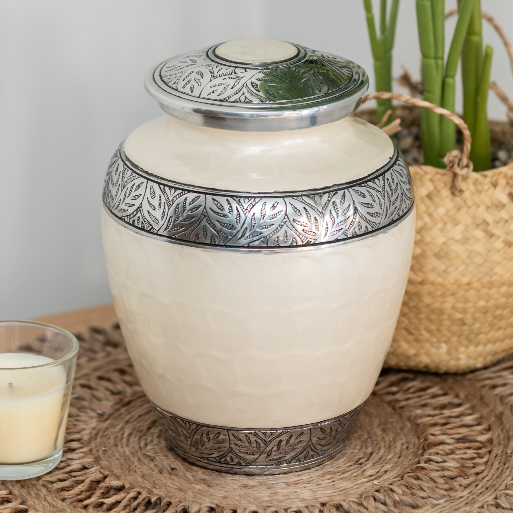 White soft scale urn with silver leaf details in natural setting