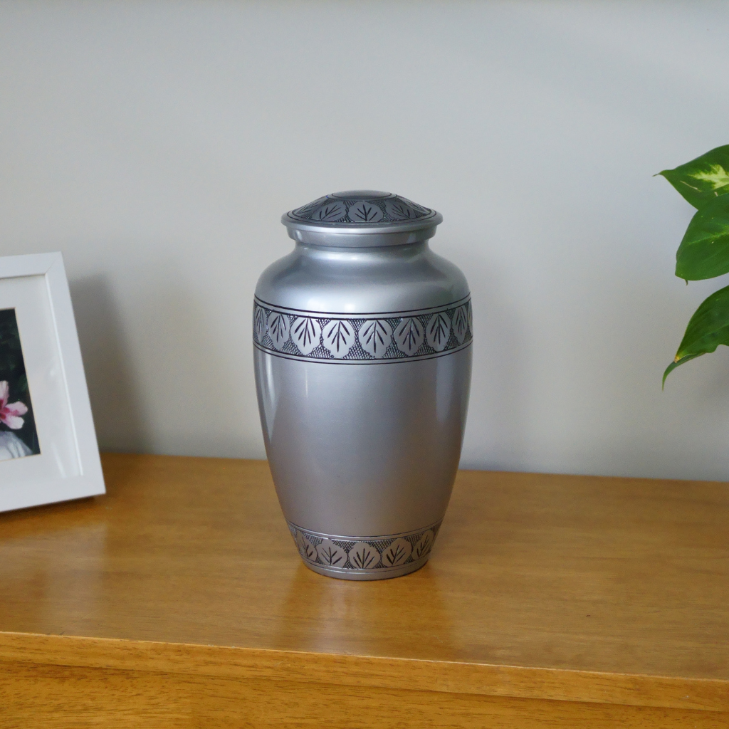 Silver pewter style urn with etched leaves in natural setting