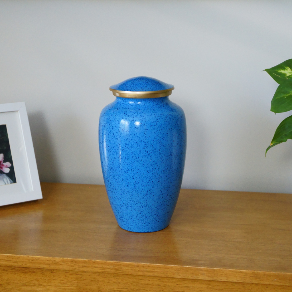 Blue urn with dark blue specked pattern and gold trim in natural setting