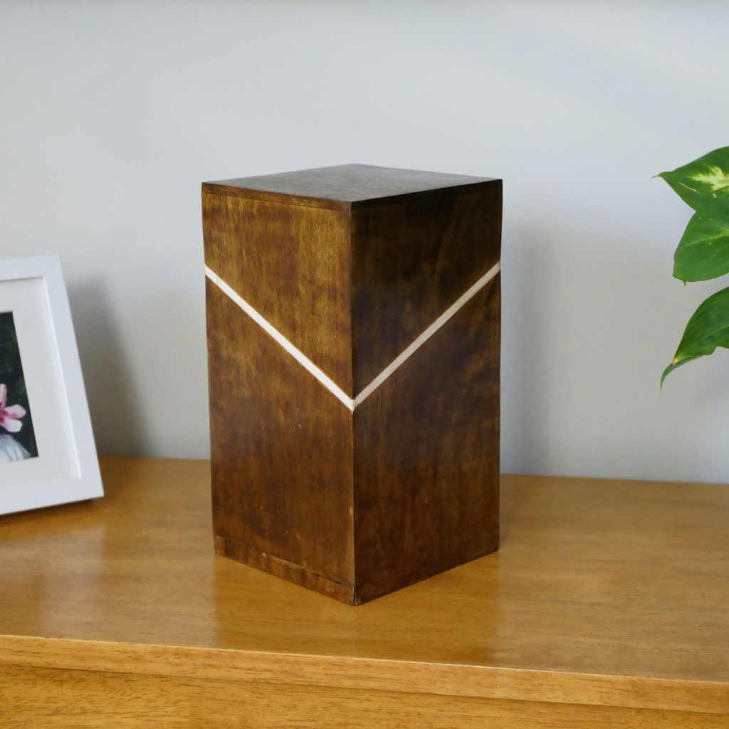 Wooden box urn with angled white line in natural setting