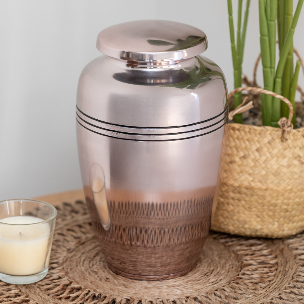 Slightly pink metallic urn with 3 black line details in natural setting