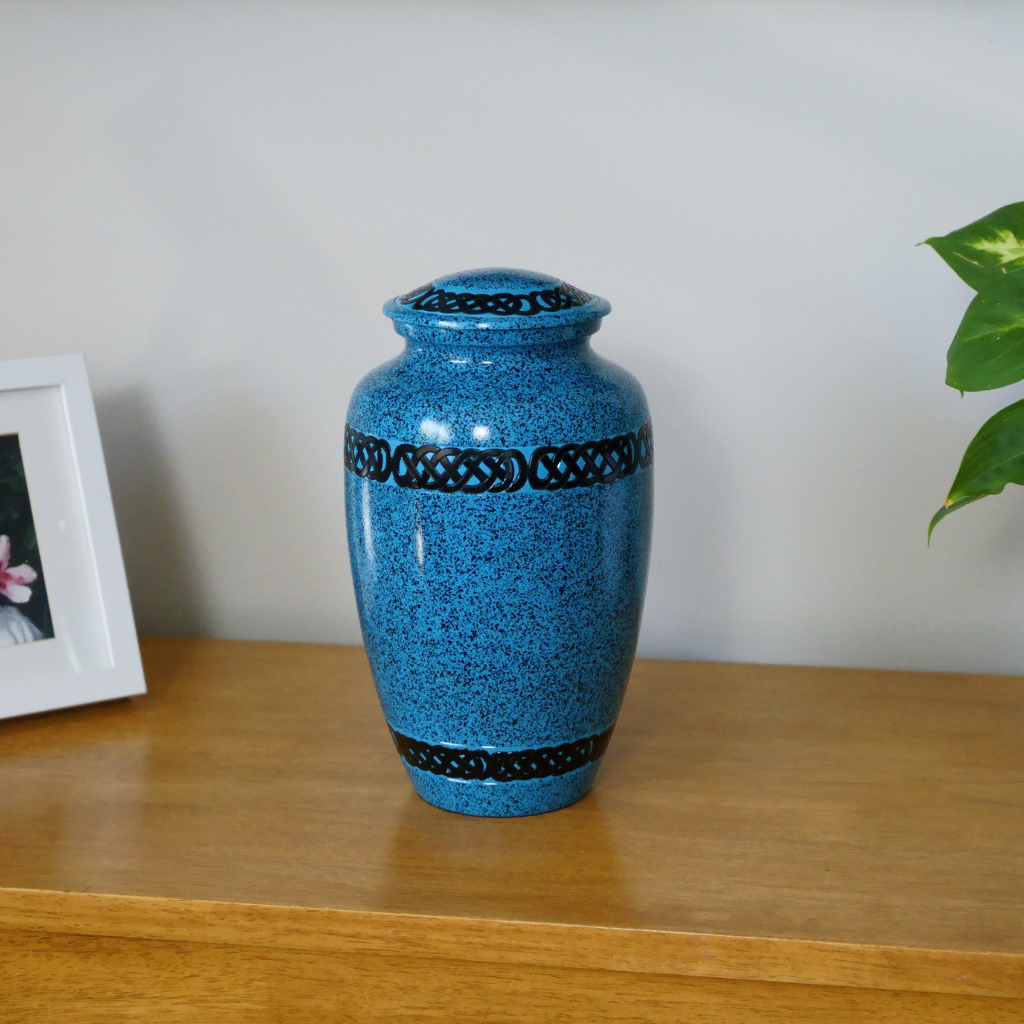 Blue urn with speckled black dots and Aztec style banded patterns in natural setting