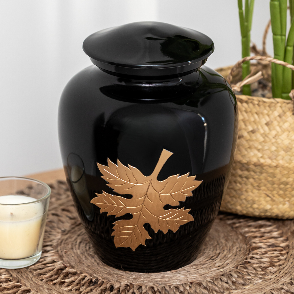 Black urn with gold autumn leaf etched in natural setting